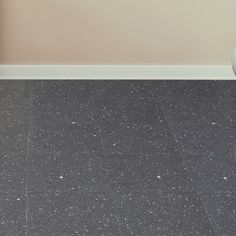 a white vase sitting on top of a floor next to a wall