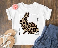 a t - shirt with an image of a leopard print rabbit on it, next to sandals