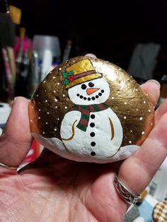 a hand holding a painted rock with a snowman on it