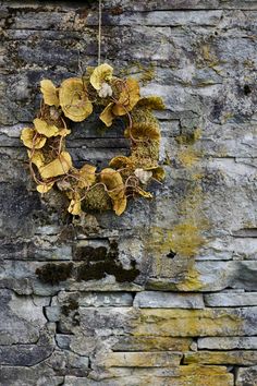 a wreath hanging on the side of a brick wall with moss growing out of it