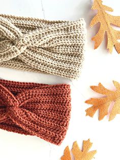 two knitted headbands laying on top of each other next to autumn leaves