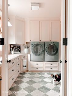 a laundry room with two washers and a dog sitting on the floor in front of it