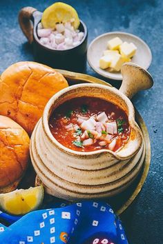 a bowl of soup next to bread and other foods