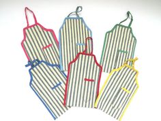 four aprons are lined up on a white surface with blue, yellow and red stripes