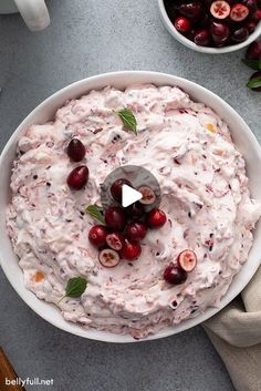 a white bowl filled with fruit and topped with a green garnish next to two bowls of cherries