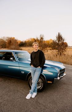 a man standing in front of a blue car