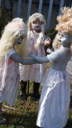 three children dressed up as zombies with long blonde hair and white makeup on their faces