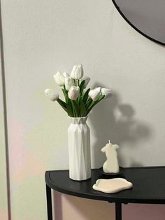 a vase with white tulips sitting on a table in front of a mirror