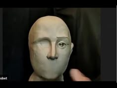 a person is holding up a clay head