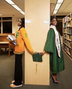 two women dressed in green and orange standing next to each other near bookshelves