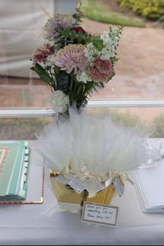 a vase filled with flowers sitting on top of a table next to an open book