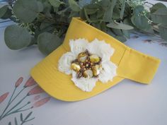 ALL ORDERS TOTALING OVER $35 SHIP FREE I designed this adorable unique yellow sun visor making an ivory flower and added a beaded shell flower accent to the center. Very Unique and cute. Perfect for the beach. Visor has velcro back. \See more hats and visor here: https://www.etsy.com/shop/theraggedyrose?ref=seller-platform-mcnav&section_id=10557807 Custom orders alway welcome. Thanks for visiting my shop. Brimmed Sun Hat For Spring, Adjustable Sun Hat For Spring Gift, Spring Gift Adjustable Sun Hat, Mini Hat Headbands As Summer Gifts, Summer Gift Mini Hats On Headband, Adjustable Yellow Mini Hats For Kentucky Derby, Adjustable Hats With Handmade Flowers For Gifts, Adjustable Hats With Handmade Flowers As Gift, Adjustable Hat With Handmade Flowers As Gift