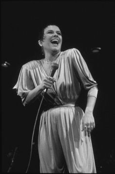 a black and white photo of a woman singing on stage with a microphone in her hand