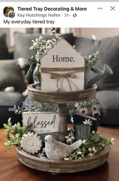 there is a small wooden house on top of a table with flowers and bird figurines