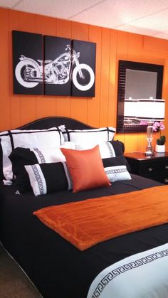 an orange and black bedroom with two motorcycles on the wall above the bed, along with other furniture