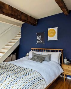 a bedroom with blue walls and white bedding in the corner, next to a stair case