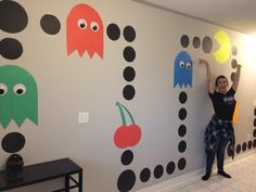 a woman standing in front of a wall decorated with paper pacman and monster faces