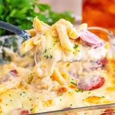 a spoon full of pasta and ham casserole being lifted from the casserole dish