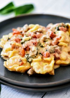 a black plate topped with pasta covered in sauce