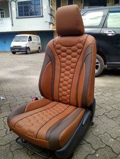 a brown and black car seat sitting on top of a parking lot next to a building