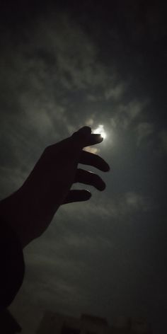 a person's hand reaching up into the sky with the moon in the background