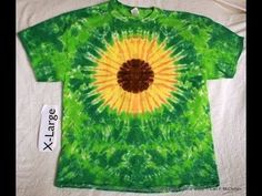 a green and yellow tie dye shirt with a brown flower on the front, next to a tag