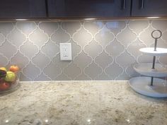 a bowl of fruit sitting on top of a counter next to a wall mounted light switch