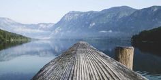 a wooden dock sitting next to a body of water with mountains in the back ground