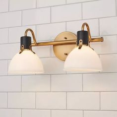 two light bathroom fixture with white and black glass shades on the wall in a public restroom