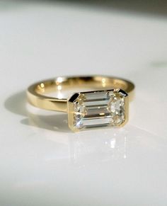 a gold ring with a baguette cut diamond on the side, sitting on a white surface