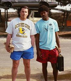 two men standing next to each other in front of a car on the street with luggage