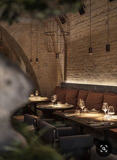 an empty restaurant with wooden tables and brown chairs, brick walls and exposed ceilinging