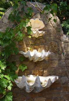 a stone wall with three white vases hanging from it's sides and ivy growing over the top