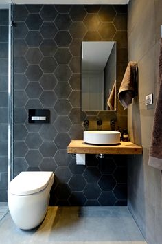 a modern bathroom with hexagonal tiles on the wall and wooden countertop, along with a white bowl sink