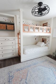 a bedroom with bunk beds, dressers and rug on the floor in front of it