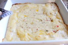 a square casserole dish filled with cheese and other toppings on a table