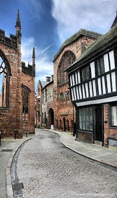 a cobblestone street lined with old buildings and arched doorways on either side