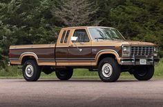 a brown pick up truck parked in front of some trees