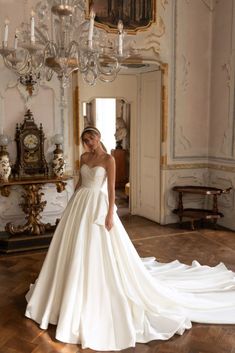 a woman in a white wedding dress standing next to a chandelier