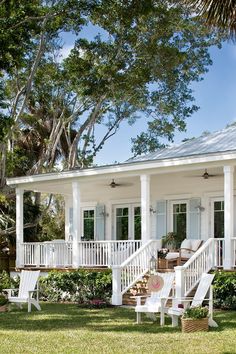 a white house with porches and chairs on the lawn