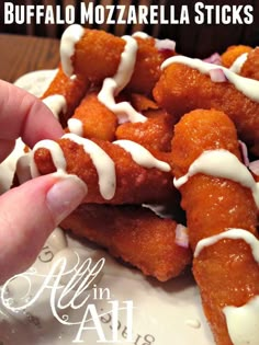 a person is holding up some food on a plate with white icing and sauce