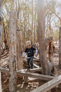 a young boy riding a skateboard on top of a wooden ramp in the woods