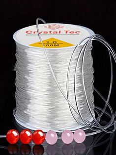 the spools of white thread are next to three red beads on a black surface