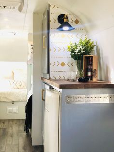 a kitchen area with a sink, dishwasher and refrigerator in it next to a bed