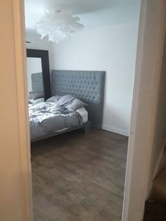 a bedroom with a bed, mirror and wooden flooring in front of the door