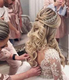 the bride is getting ready to go into her wedding dress with her hair and makeup artist