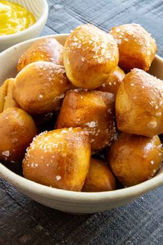 a bowl full of doughnuts sitting on top of a table next to some dipping sauce