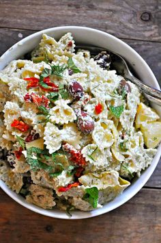 a white bowl filled with pasta salad on top of a wooden table