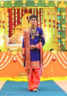 a man standing in front of a stage wearing a blue and orange outfit with gold accents