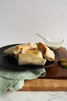 some food is on a black plate with a green napkin and a white bowl in the background